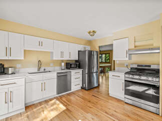 This kitchen boasts modern white cabinetry with elegant brass hardware, complemented by sleek quartz countertops.