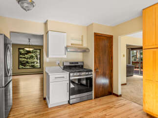 Discover this charming kitchen featuring a sleek stainless steel gas range and modern white cabinetry, complemented by a durable quartz countertop.