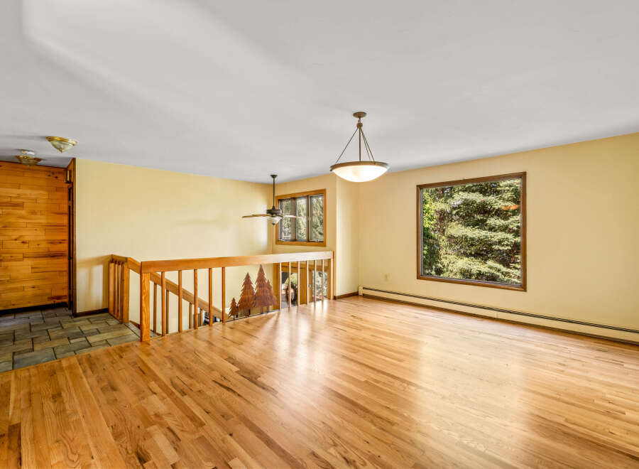 Step into this inviting living space featuring gleaming hardwood floors and a large window offering picturesque views of lush greenery.