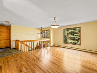 Step into this inviting living space featuring gleaming hardwood floors and a large window offering picturesque views of lush greenery.