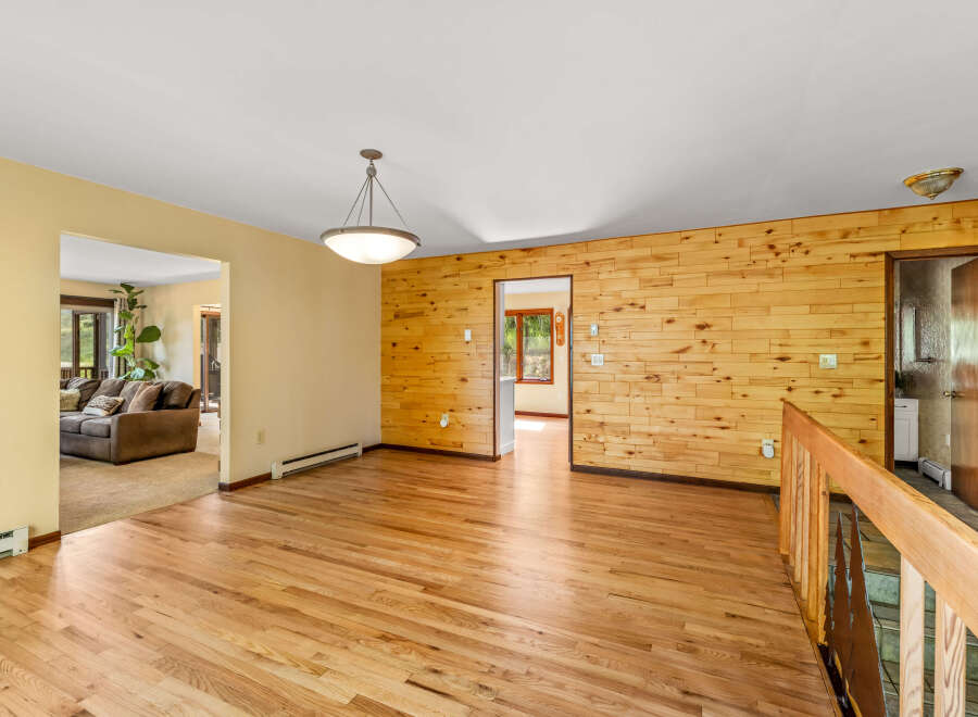 Step into this inviting living space featuring warm hardwood floors and a striking wood-paneled accent wall.