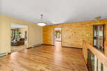 Step into this inviting living space featuring warm hardwood floors and a striking wood-paneled accent wall.
