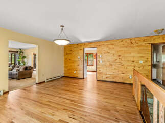 Step into this inviting living space featuring warm hardwood floors and a striking wood-paneled accent wall.