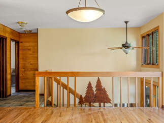 This charming interior features warm wood paneling and a beautiful wooden staircase with a unique tree silhouette design.
