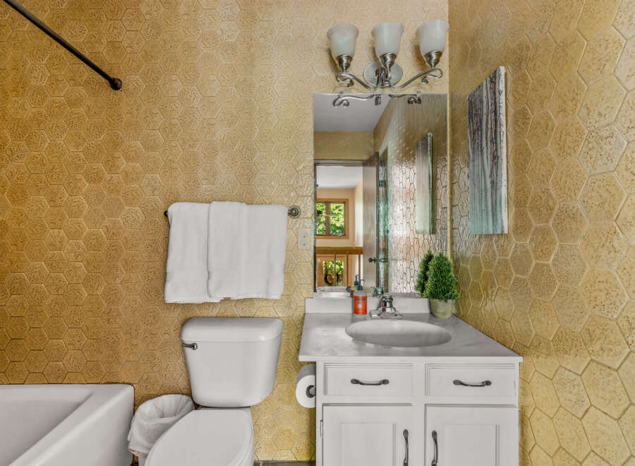 This charming bathroom features a hexagonal textured tile accent wall in a warm, golden hue, adding a unique visual element.