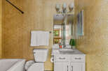 This charming bathroom features a hexagonal textured tile accent wall in a warm, golden hue, adding a unique visual element.