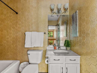 This charming bathroom features a hexagonal textured tile accent wall in a warm, golden hue, adding a unique visual element.