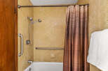 This accessible bathroom features a bathtub with a showerhead, grab bars for safety, and a convenient soap dish.