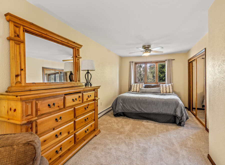 This cozy bedroom features a spacious wooden dresser with a large mirror, perfect for storing your belongings and getting ready.