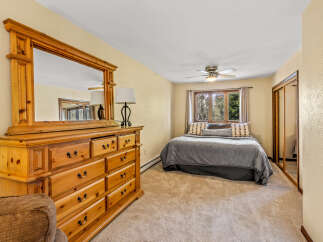 This cozy bedroom features a spacious wooden dresser with a large mirror, perfect for storing your belongings and getting ready.
