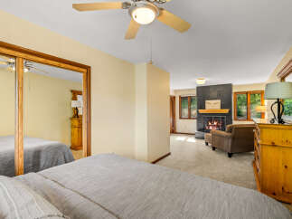 Experience ultimate comfort in this spacious bedroom featuring two cozy beds and a relaxing seating area with a fireplace.