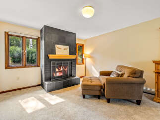 Cozy up by the inviting fireplace in this charming living room, featuring a striking black tile surround and a warm wooden mantel.