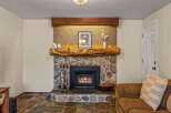 Cozy up by the stone fireplace, featuring a rustic log mantel and a modern insert with a crackling fire.