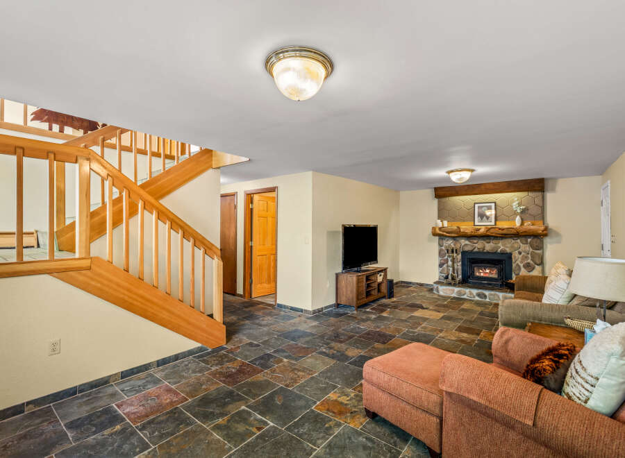 Cozy up by the stone fireplace in this inviting living space, featuring a rustic wooden mantel and a warm ambiance.