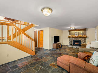Cozy up by the stone fireplace in this inviting living space, featuring a rustic wooden mantel and a warm ambiance.