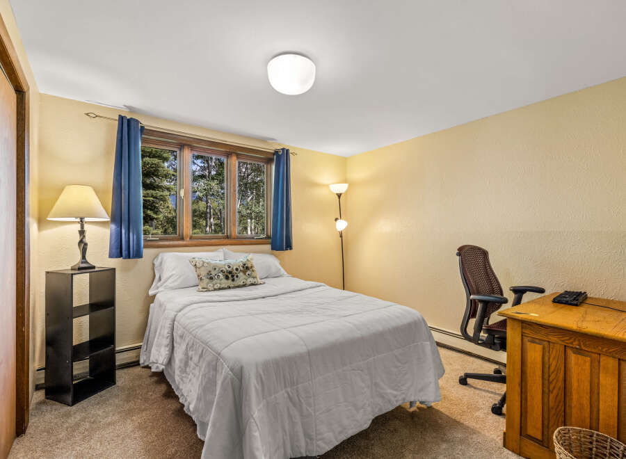 This cozy bedroom features a comfortable queen-size bed dressed in crisp white linens, perfect for a restful night's sleep.