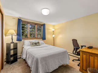 This cozy bedroom features a comfortable queen-size bed dressed in crisp white linens, perfect for a restful night's sleep.