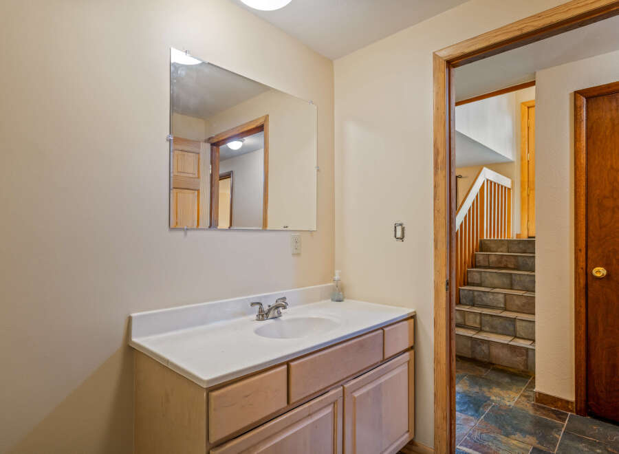 This bathroom features a light wood vanity with a white countertop and a modern chrome faucet.