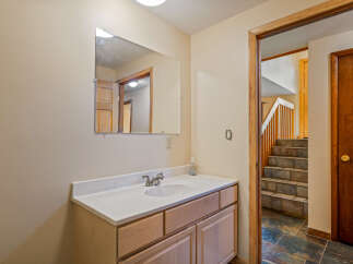 This bathroom features a light wood vanity with a white countertop and a modern chrome faucet.