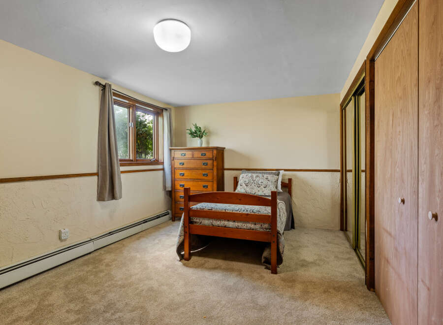 Discover this cozy bedroom featuring a charming wooden bed and a classic dresser, perfect for a comfortable living space.