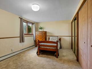 Discover this cozy bedroom featuring a charming wooden bed and a classic dresser, perfect for a comfortable living space.