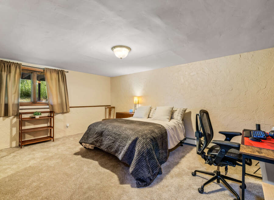 This cozy bedroom features a comfortable queen-size bed with a dark quilted comforter, perfect for a restful night's sleep.