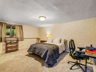 This cozy bedroom features a comfortable queen-size bed with a dark quilted comforter, perfect for a restful night's sleep.