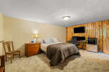 This bedroom offers a cozy retreat with a comfortable bed, a functional workspace with dual monitors, and ample storage.