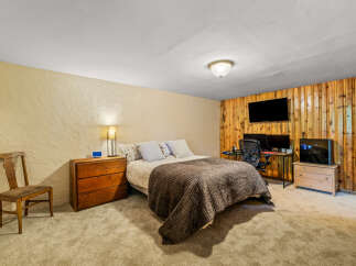 This bedroom offers a cozy retreat with a comfortable bed, a functional workspace with dual monitors, and ample storage.