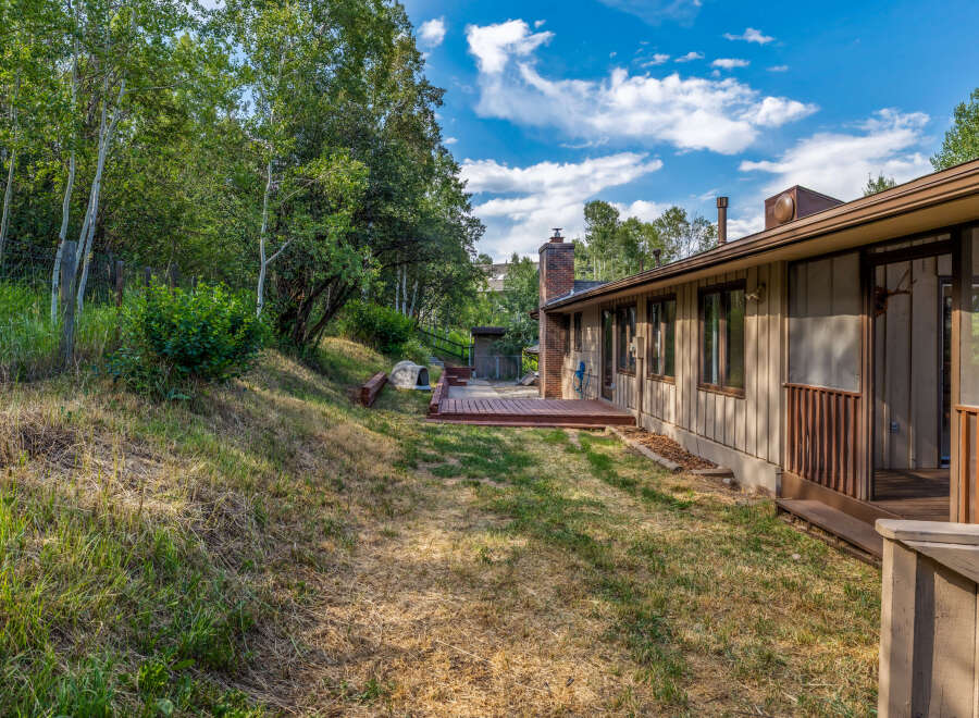 Enjoy the serene backyard of this property, featuring a spacious wooden deck perfect for outdoor entertaining and relaxation.