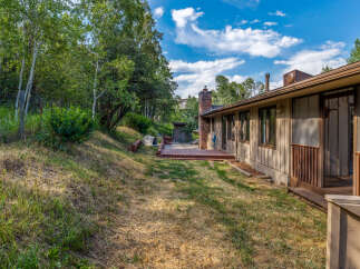 Enjoy the serene backyard of this property, featuring a spacious wooden deck perfect for outdoor entertaining and relaxation.