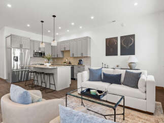 Experience modern living in this open-concept space, featuring a sleek gray kitchen with stainless steel appliances and a granite-topped island perfect for casual dining.