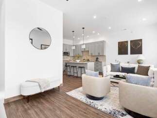 Experience modern living in this stunning open-concept space, featuring a sleek grey kitchen with ample cabinet storage and a spacious island perfect for entertaining.