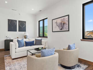 Experience modern living in this stylish living room, featuring a plush white sofa adorned with elegant blue and gray accent pillows.