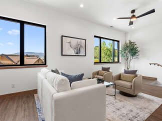 Experience modern living in this spacious living room, featuring large windows with scenic views and a comfortable seating area.