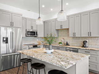 Experience modern luxury in this stunning kitchen, featuring sleek grey cabinetry and a spacious granite island perfect for entertaining.