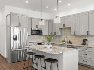 Experience modern luxury in this stunning kitchen, featuring sleek grey cabinetry and a spacious granite island perfect for entertaining.