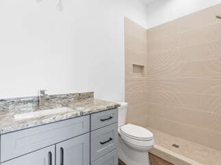 This modern bathroom features a sleek gray vanity with a granite countertop and a contemporary chrome faucet.