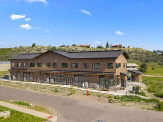 Discover this modern commercial building featuring a warm wood exterior and a sleek dark roof, perfect for businesses seeking a professional and inviting space.