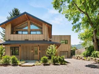Experience modern mountain living in this stunning wood-clad home, featuring a striking A-frame roof and expansive triangular windows that capture breathtaking views.