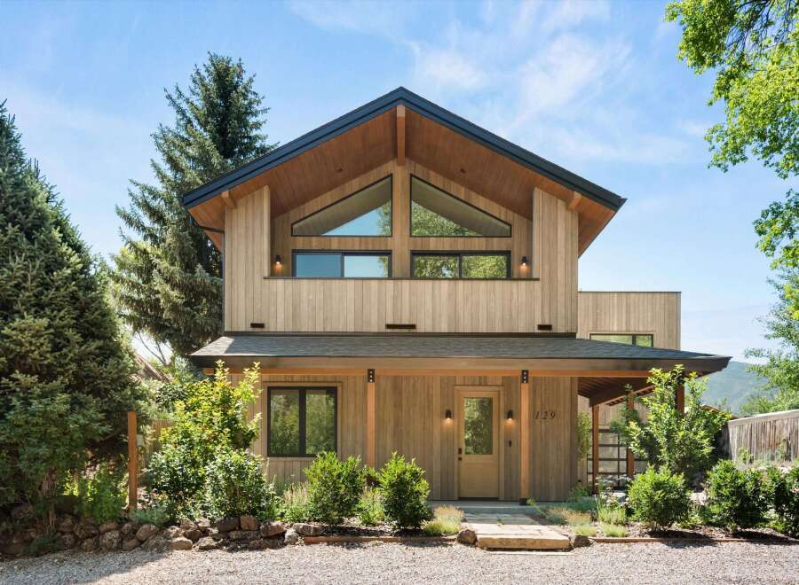 Experience modern mountain living in this stunning wood-clad home, featuring a striking asymmetrical roofline and expansive triangular windows that flood the interior with natural light.
