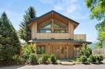 Experience modern mountain living in this stunning wood-clad home, featuring a striking asymmetrical roofline and expansive triangular windows that flood the interior with natural light.