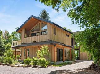 Discover modern living in this stunning wood-clad home, featuring a striking asymmetrical roofline and expansive triangular windows that flood the interior with natural light.