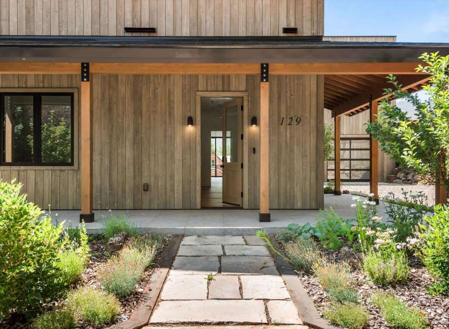 Experience modern living with this stunning home featuring a natural wood exterior and a welcoming covered porch.