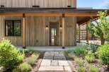 Experience modern living with this stunning home featuring a natural wood exterior and a welcoming covered porch.