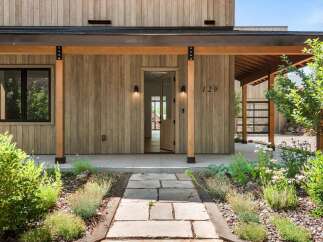 Experience modern living with this stunning home featuring a natural wood exterior and a welcoming covered porch.