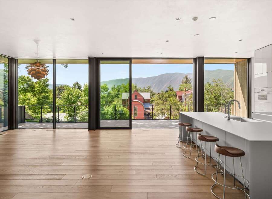 Experience breathtaking mountain views from this modern kitchen, featuring a sleek island with bar seating and expansive floor-to-ceiling windows.