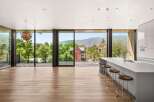 Experience breathtaking mountain views from this modern kitchen, featuring a sleek island with bar seating and expansive floor-to-ceiling windows.