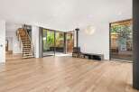 Experience modern living in this spacious open-concept living area featuring a striking floating staircase and a contemporary wood-burning stove.