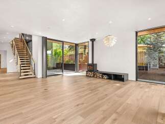 Experience modern living in this spacious open-concept living area featuring a striking floating staircase and a contemporary wood-burning stove.